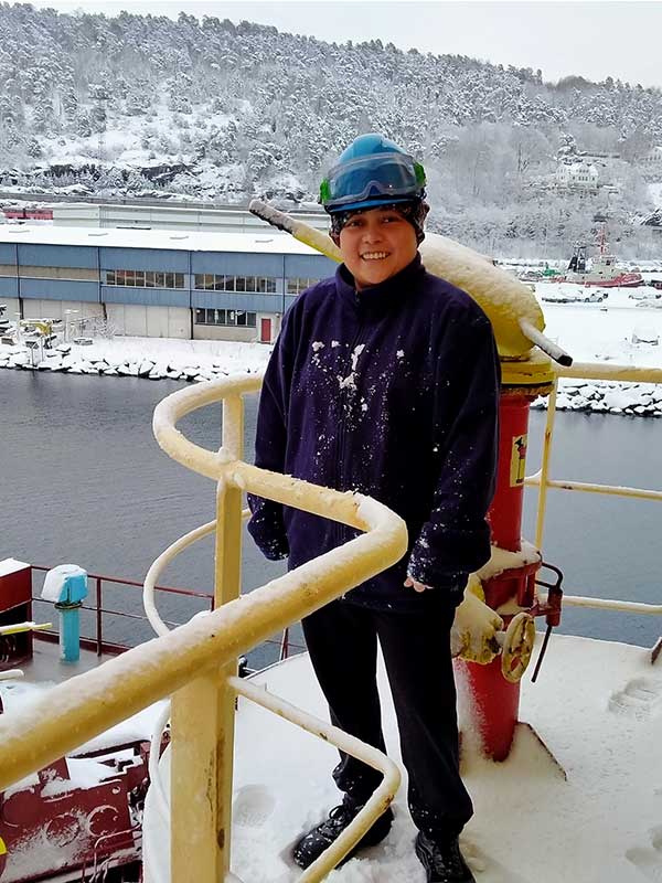 Myline B. Namora standing on the deck of the Synergy managed vessel with the sea in the background