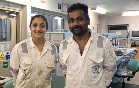 5th Engineer Hifa Salim and the 2nd Officer smiling together in boiler suits inside the control room.