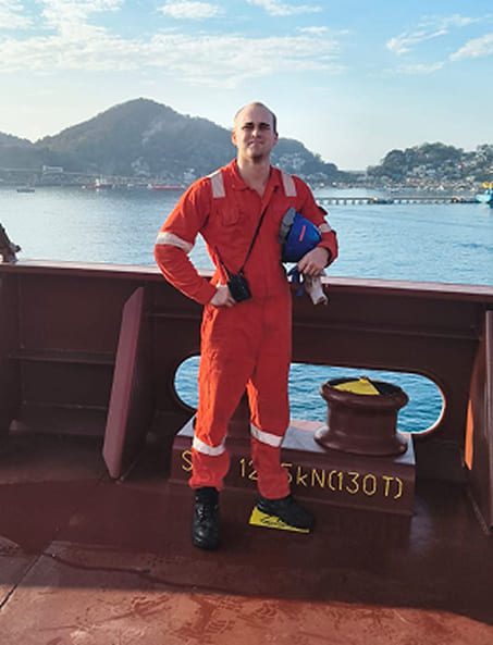Jamie standing on a ship's deck near mooring equipment.