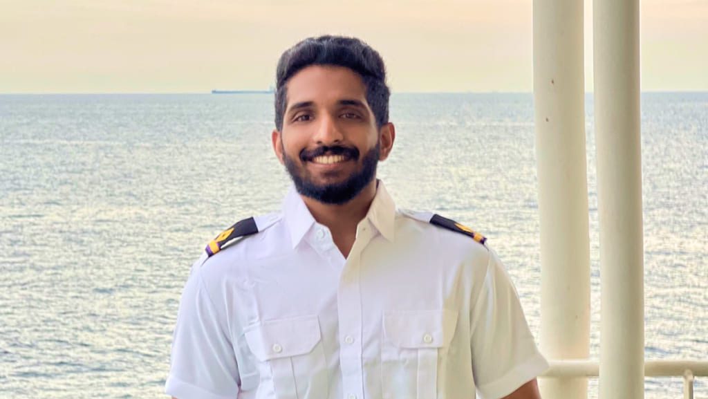 Portrait of 4th Engineer Sidharth Dharmarajan in a white officer uniform on the deck of the Stena Contender with an ocean backdrop.