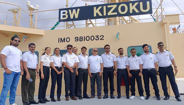Group portrait of the ship officers and crew standing together on the deck of the Synergy Marine Group vessel BW Kizoku.