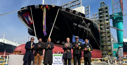 Dignitaries standing in front of the 15,500 TEU LNG dual-fuel container vessel YM Worthiness during its delivery ceremony.